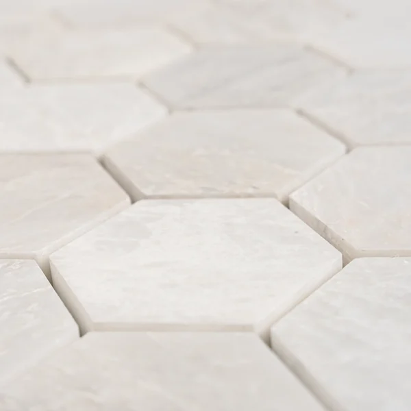 Close-up of 2-inch honed Iceberg marble honeycomb mosaic tiles with white hexagon pattern and soft matte texture.