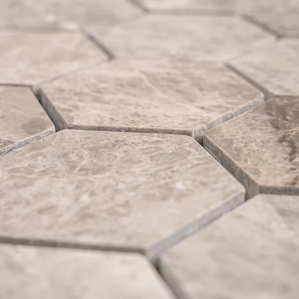 Side view of silver honeycomb marble tile showing polished finish and edge thickness over mesh backing.