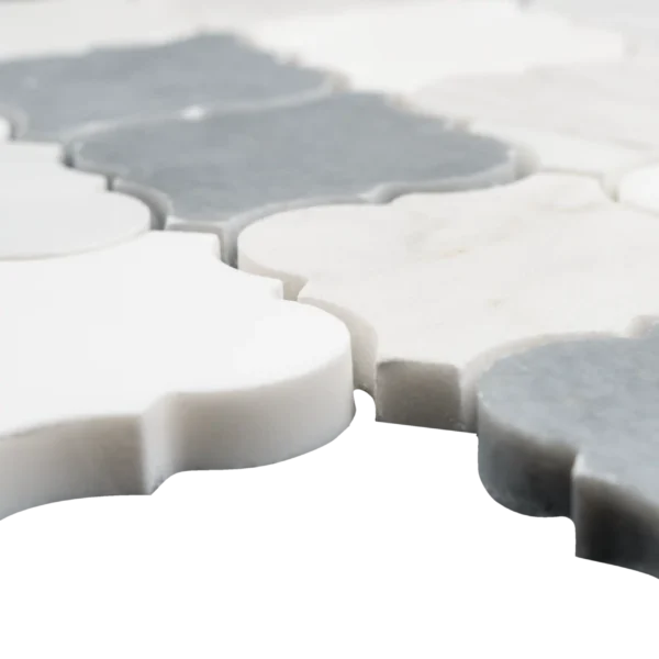 Close-up view of interlocking arabesque-shaped marble mosaic tiles in white, and dark gray tones with a polished surface, highlighting the thickness and smooth edges.