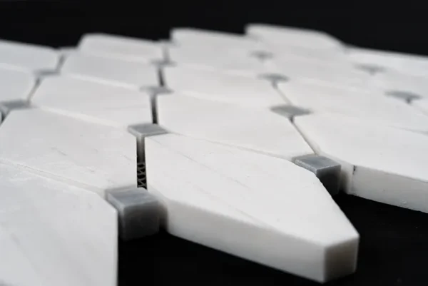 Close-up of clipped diamond polished marble mosaic tile with Dolomite and gray stone blend showing thickness and mesh backing