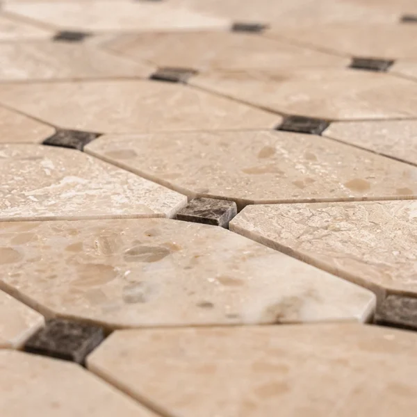 Close-up of polished Royal Beige and Emperador marble mosaic tile in clipped diamond design with dark dot accents