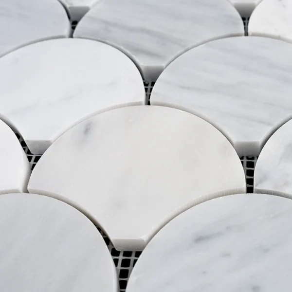 Close-up of fish scale Carrara marble mosaic tiles with polished finish and delicate light gray veining in soft white tones