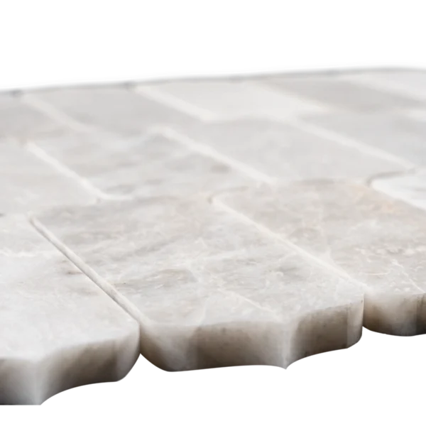 Angled view of a Dorema Dolomite marble mosaic sheet, featuring rectangular tiles with rounded ends arranged in a seamless, repeating pattern.