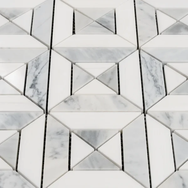 A close-up detail of a marble mosaic with diamond and triangular shapes, showing the fine grout lines and the polished finish of the stone.