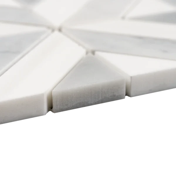 A detailed macro shot of a marble mosaic tile pattern with diamond and triangular shapes. The image captures the texture and subtle color variations of the stone.