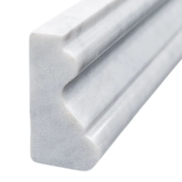 Close-up side angle of Carrara marble crown molding, highlighting the detailed curve and glossy surface.