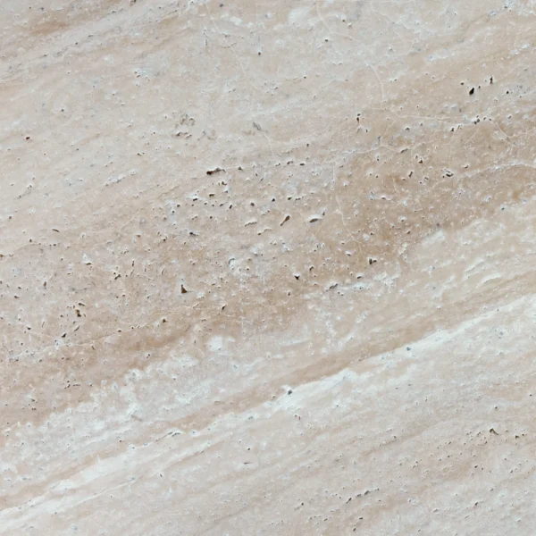 Close-up of Desert Bloom 16"x24" tumbled travertine paver highlighting natural texture, surface pits, and warm beige veining for a rustic outdoor finish