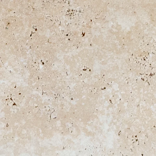 Close-up of ivory travertine paver showcasing porous tumbled surface and warm natural stone character