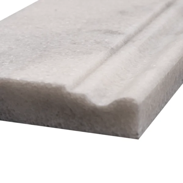 Close-up of honed Milas white marble baseboard trim showing subtle veining and edge profile.