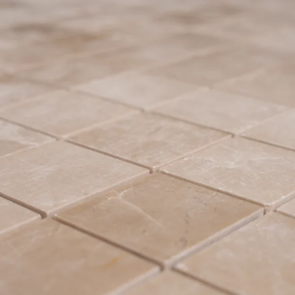 Close-up angled view of Botticino 2x2 polished marble mosaic tiles showing smooth texture and subtle veining.