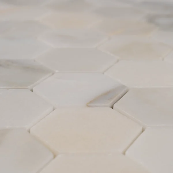 Close-up of Calacatta honeycomb mosaic tile showing smooth honed finish and natural marble veining details.