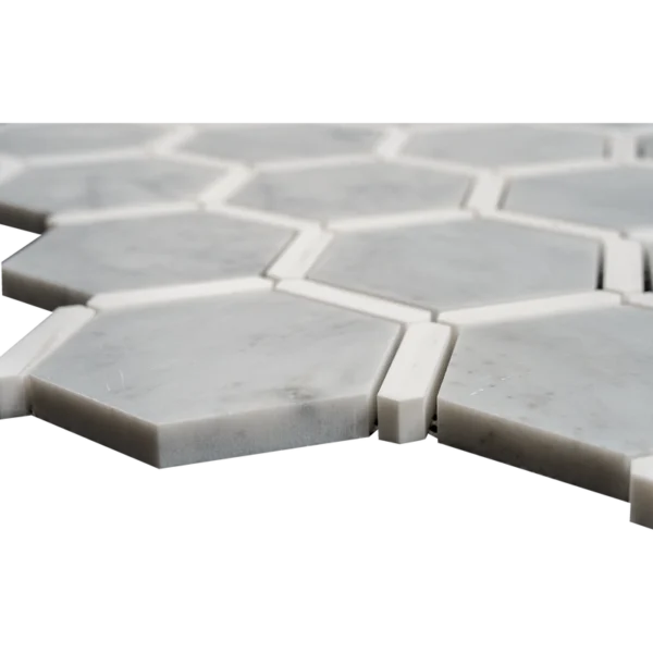 Side angle view of Carrara marble hexagon mosaic tiles with Dolomite trim, highlighting polished edges.