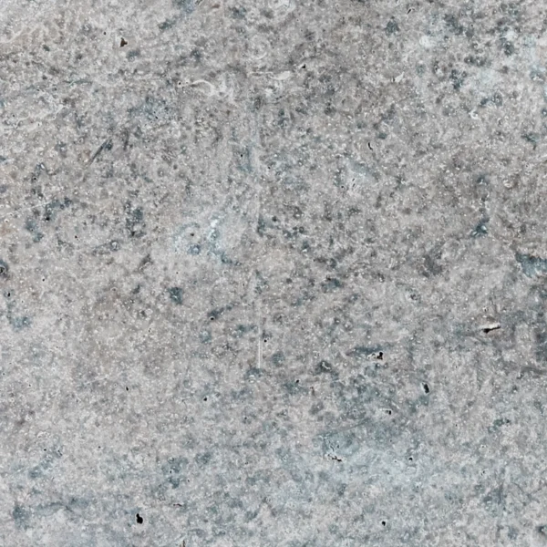 Close-up of Charcoal tumbled travertine paver highlighting detailed texture, soft pits, and multi-tonal gray color patterns.