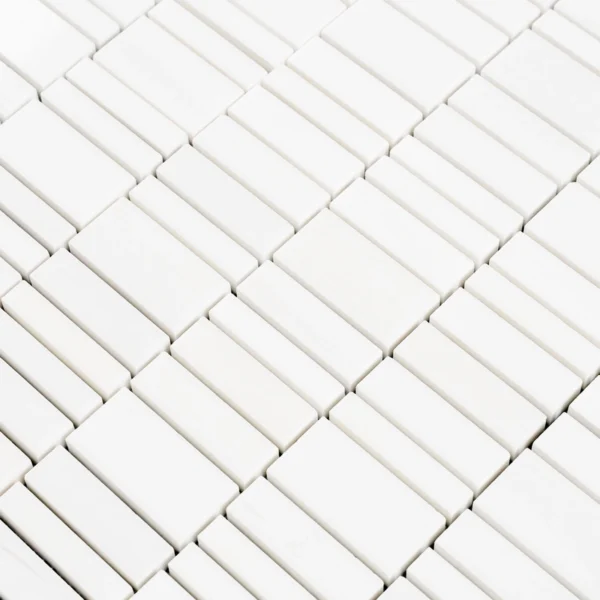 Close-up at an angle showing the polished white dolomite strips with subtle veining and tight grout joints.