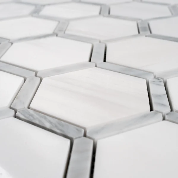 Close-up angled view showing the smooth polished surface of the white hexagonal marble tiles with gray Carrara accents between them.