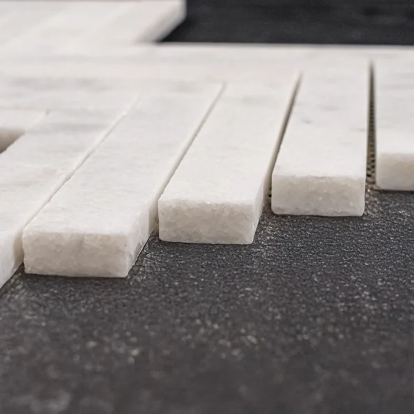 Macro close-up of Milas White 1x6 honed marble mosaic tiles, highlighting the textured edges, thickness, and honed surface finish.