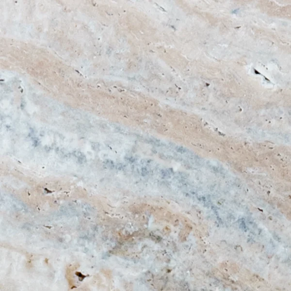 showing tumbled matte texture, small natural pits, and sweeping blue-gray ribbons on warm beige.