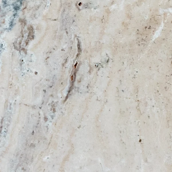 Close-up of Norwegian River 6"x12" tumbled travertine paver showing a warm beige/ivory base with flowing gray-taupe veining, scattered natural pits, and a soft matte texture.