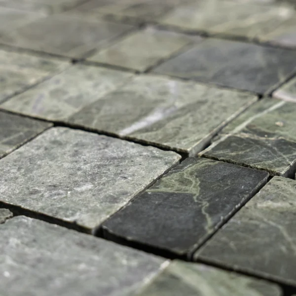 Angled close-up showing the honed finish and lightly chiseled edges; color variation from sage to deep green with natural veining.