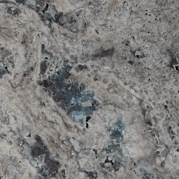 Close-up detail of the Silver tumbled travertine showing mottled silver/charcoal areas with blue-gray swirls and open pores typical of travertine.
