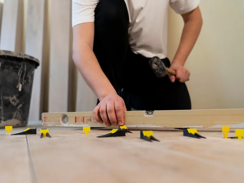 Improper natural stone tile installation showing leveling tools and spacers during floor installation