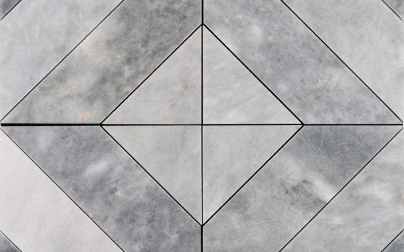 Top view of Piela Bardiglio Polished marble mosaic tile sheet featuring a bold geometric diamond pattern with diagonally cut light and dark grey marble pieces.